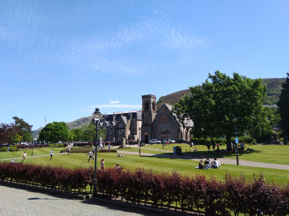 Bâtiment historique dans un parc avec des personnes se relaxant sur l'herbe.