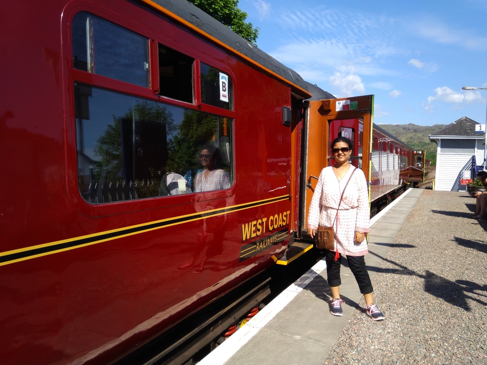 Personne se tenant devant un train rouge dans une gare.