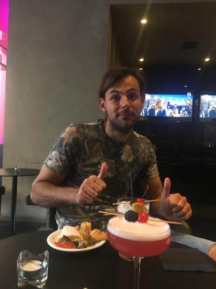 Homme levant le pouce dans un café avec une boisson.