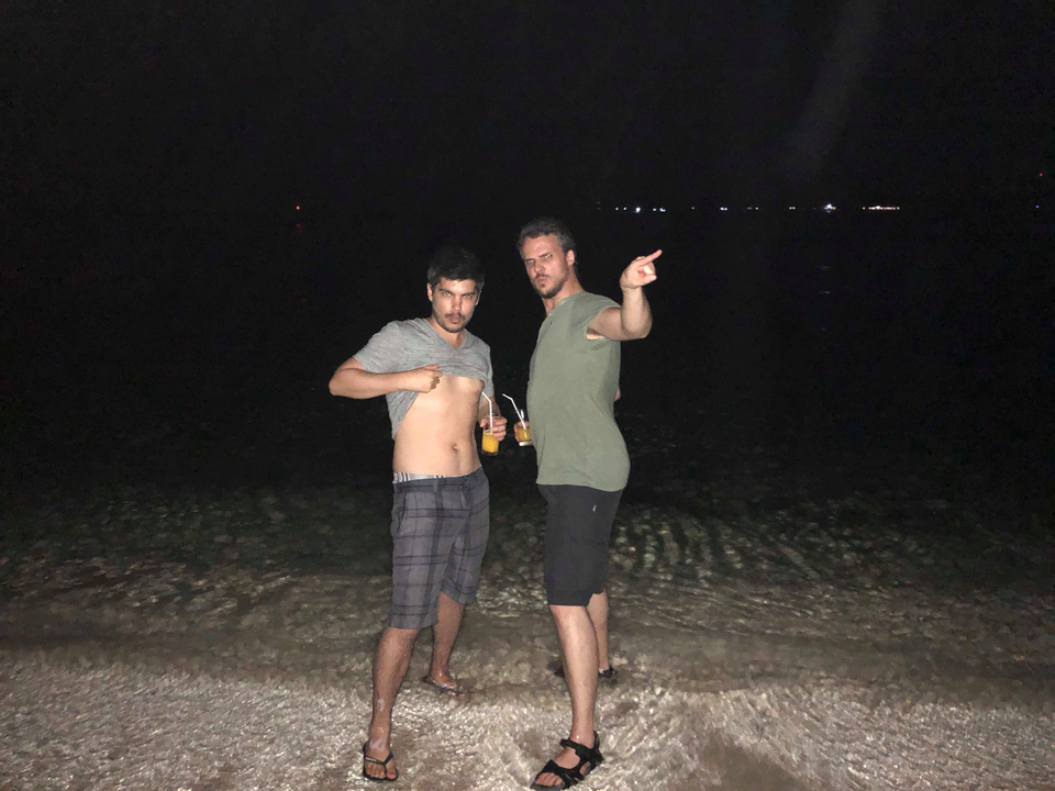 Two people on a beach at night with drinks.