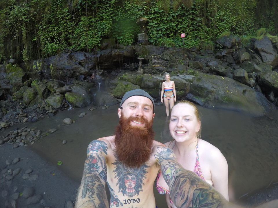 People posing for a selfie by a rock formation.