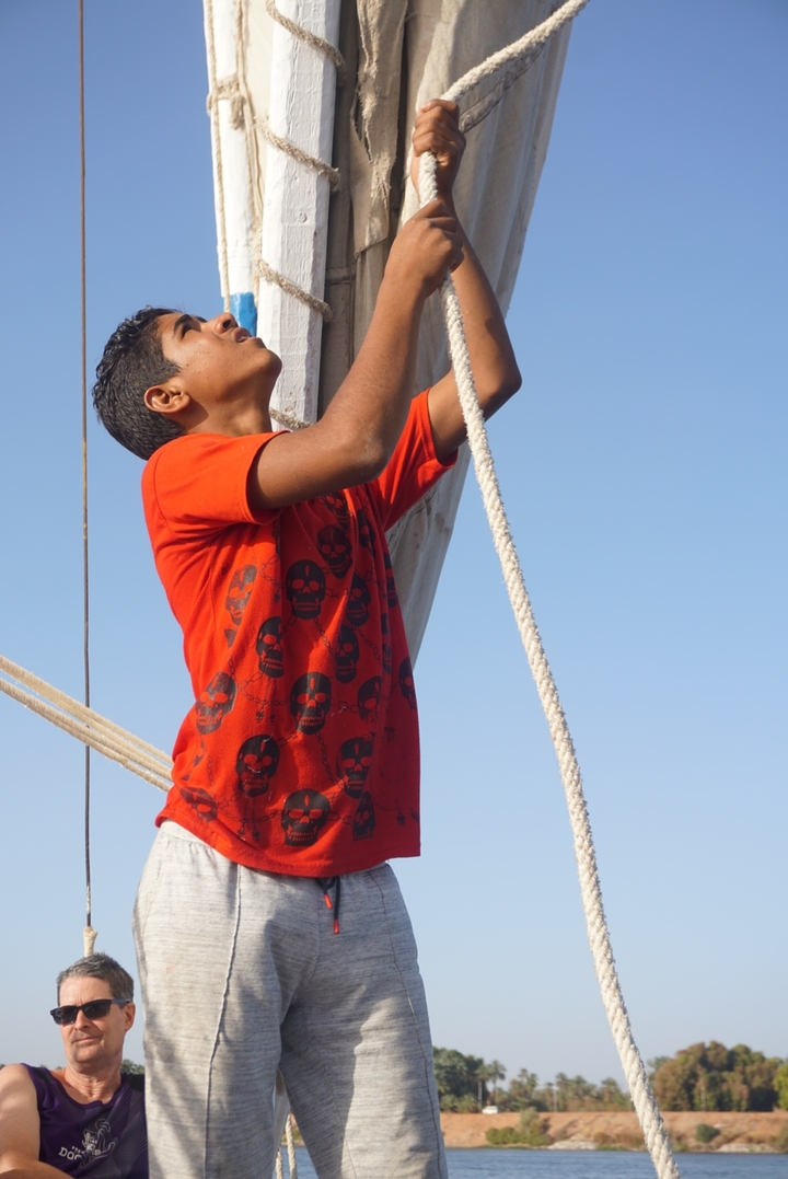 Un garçon ajuste les voiles d'un bateau traditionnel.