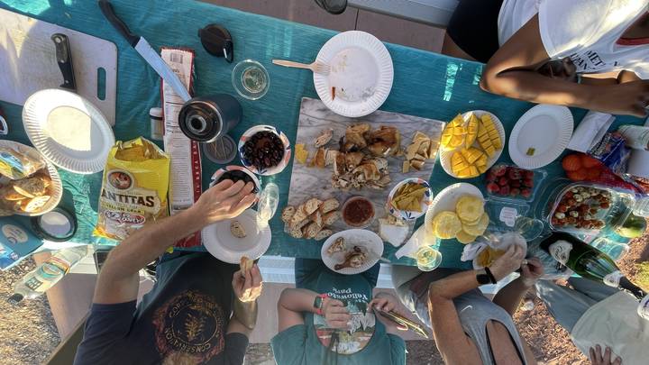 Une table de pique-nique avec des aliments et des personnes assises autour.