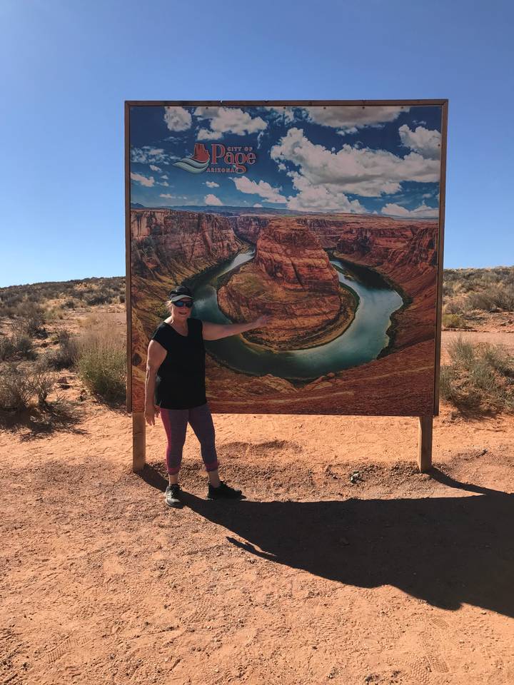 Personne posant avec une affiche de Horseshoe Bend.