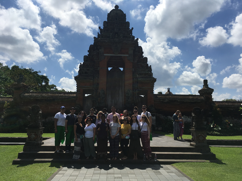 Group of people in front of a temple with cloudy sky.