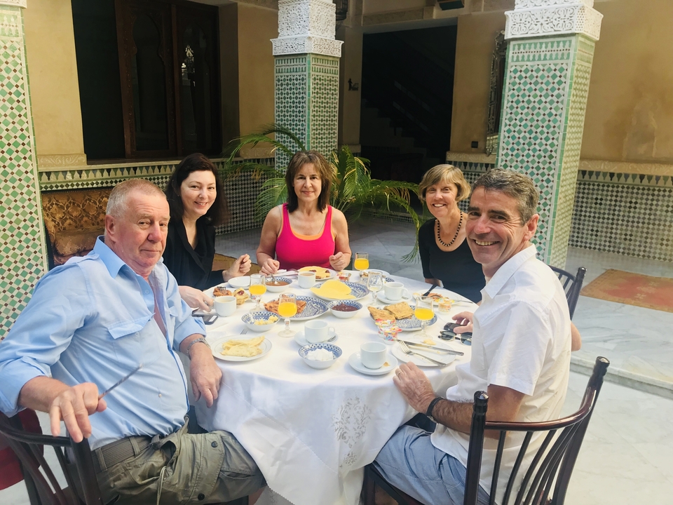 Un groupe de personnes prenant leur petit-déjeuner dans une cour traditionnelle.