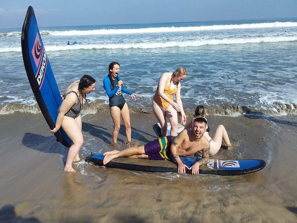 Group of people on a beach having fun with surfboards.