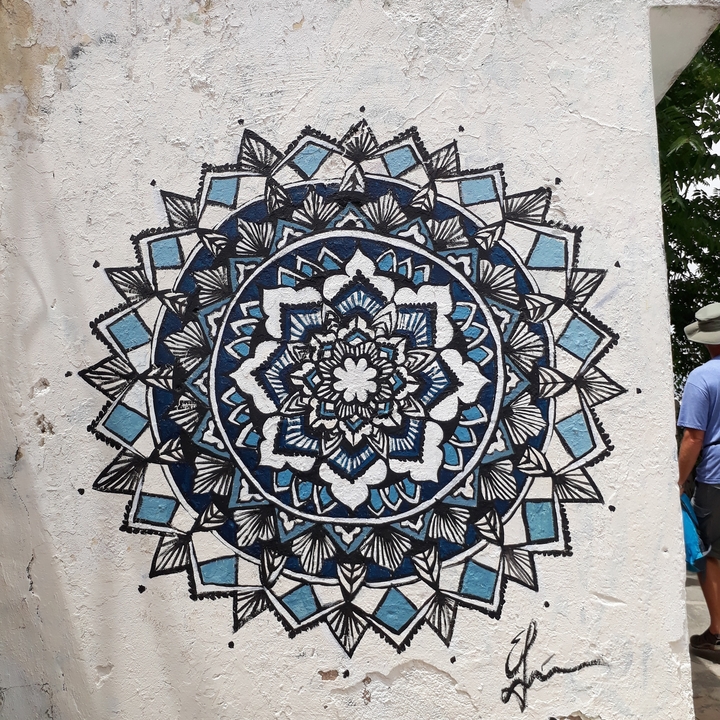 Mur décoratif avec un grand dessin de mandala et un homme dans le coin.