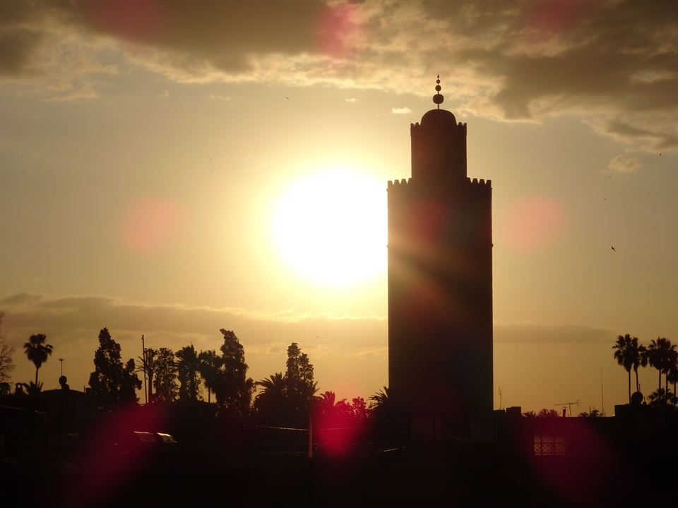 Silhouette d'une tour de mosquée sur fond de coucher de soleil.