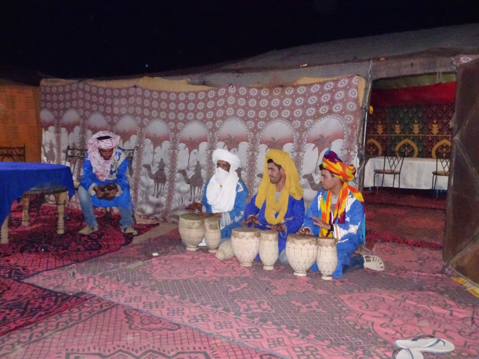 Groupe de musiciens en tenue traditionnelle à l'intérieur d'une tente.