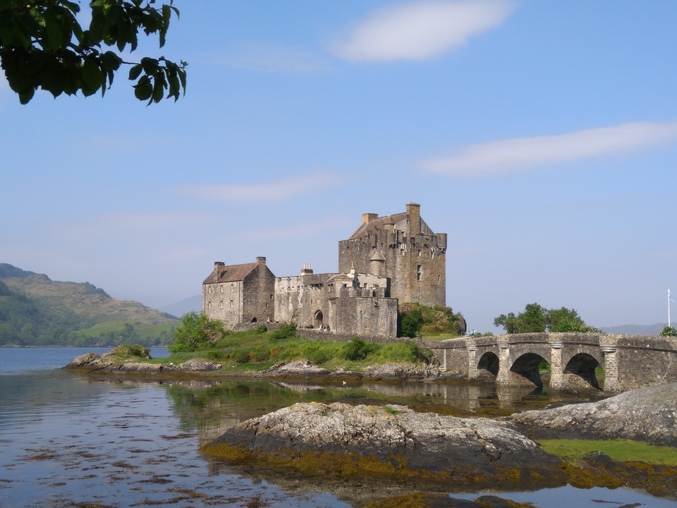 Le château d'Eilean Donan avec un pont et une vue sur l'eau.