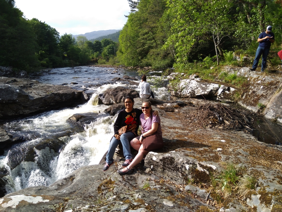 Deux femmes assises sur des rochers au bord d'une rivière.