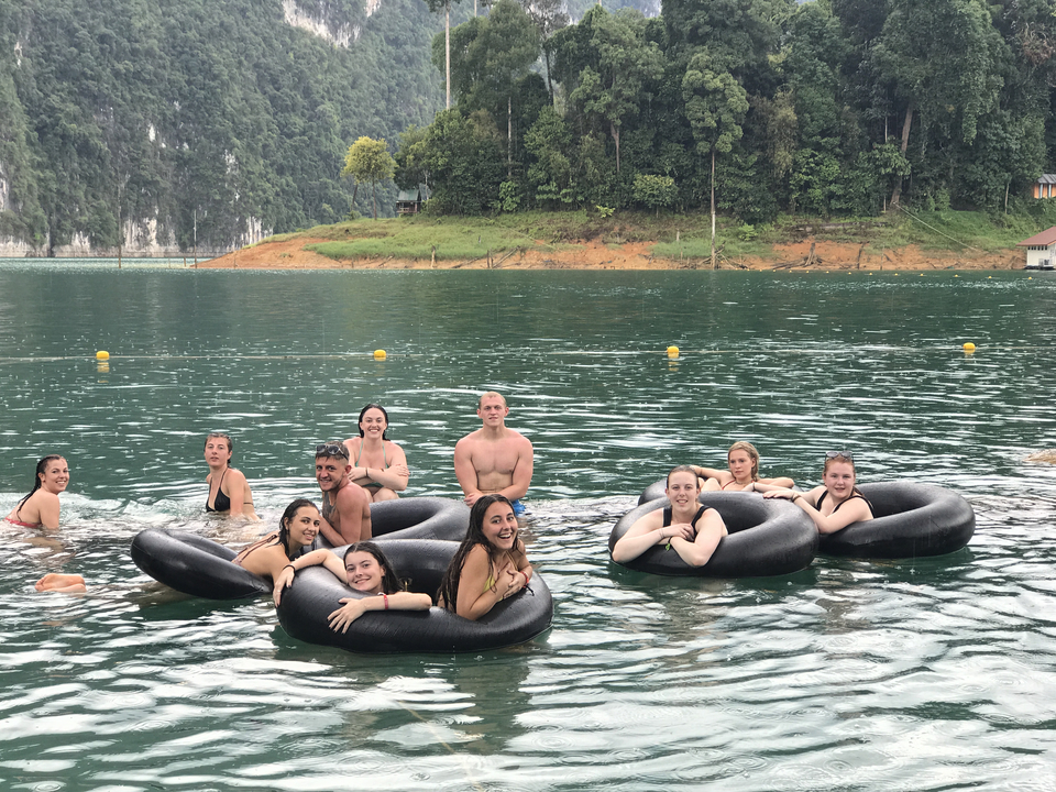 Group of people enjoying floating in inner tubes on a lake.