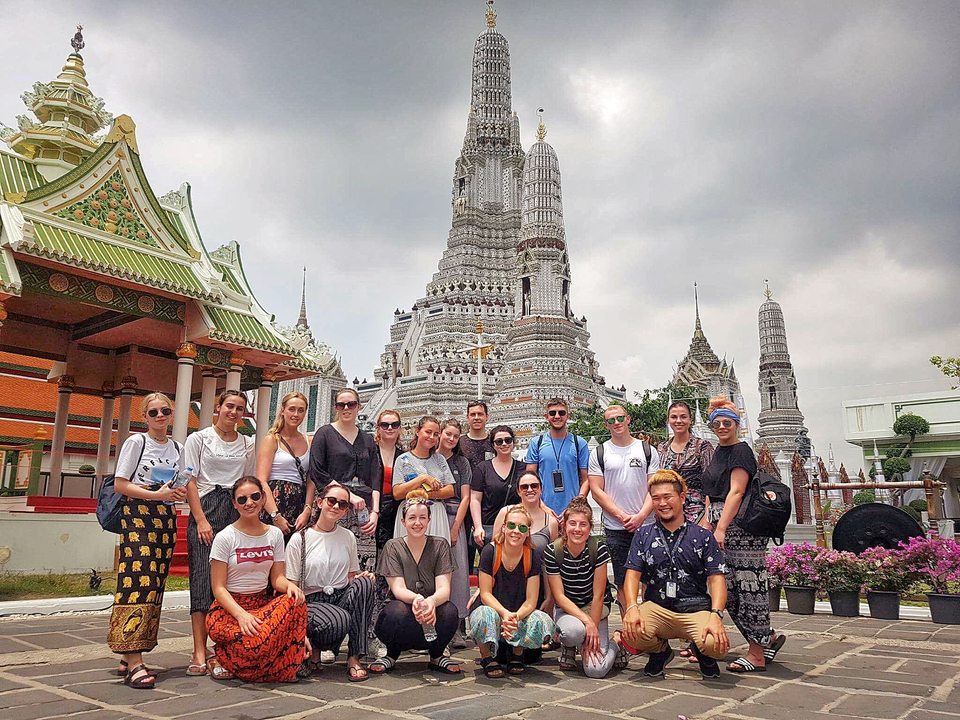 Tour group in front of a temple complex with spires.