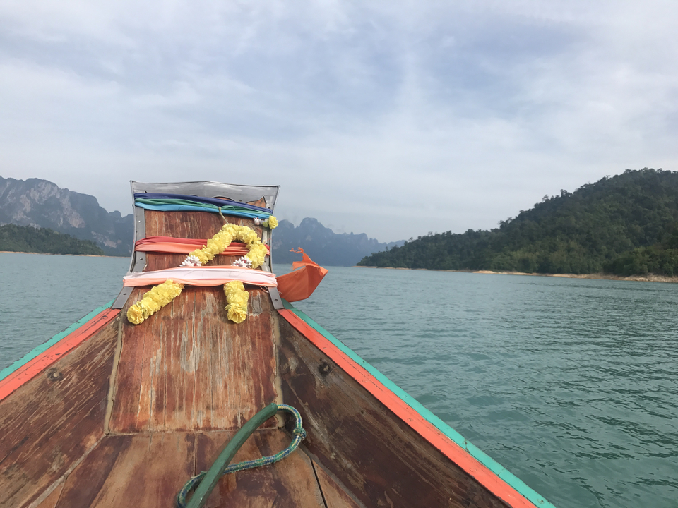 Proue d'un bateau ornée de rubans sur un lac calme.