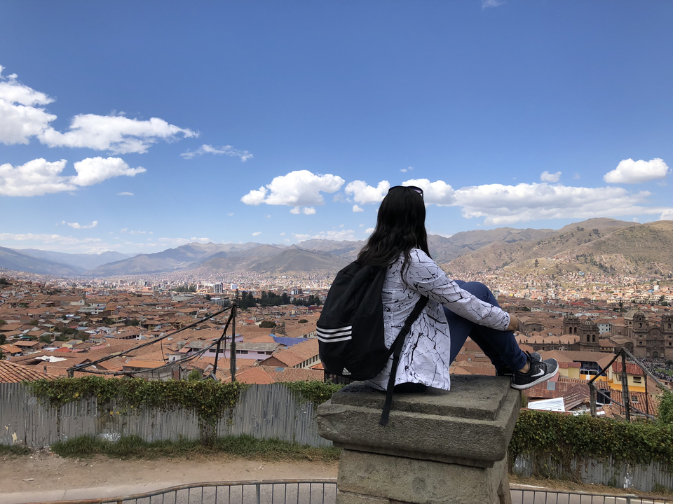 Femme assise sur un toit surplombant la ville de Cusco.