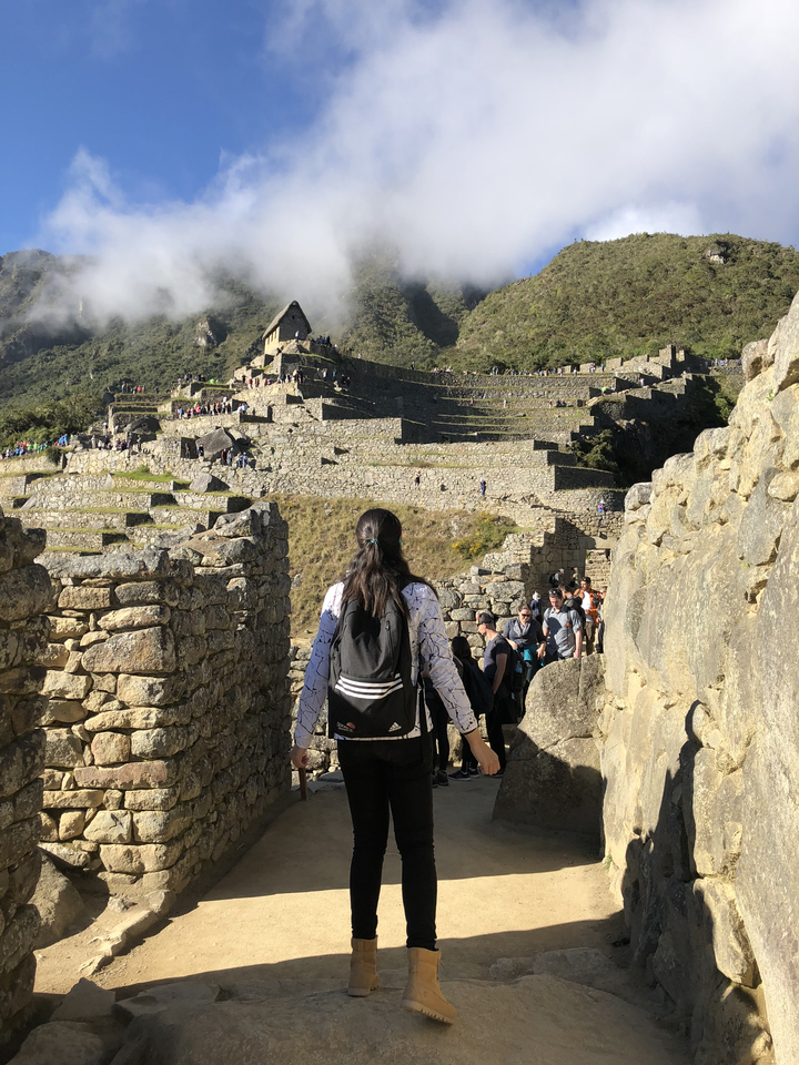 Groupe de personnes marchant dans les ruines de Machu Picchu, où l'on peut voir des terrasses et des structures en pierre.
