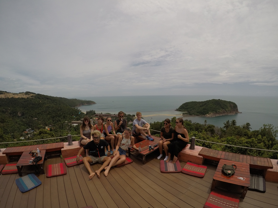 Groupe de personnes profitant d'une vue panoramique sur l'océan depuis une terrasse.