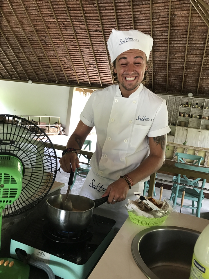 Personne en uniforme de chef cuisinier debout dans un environnement de cuisine.