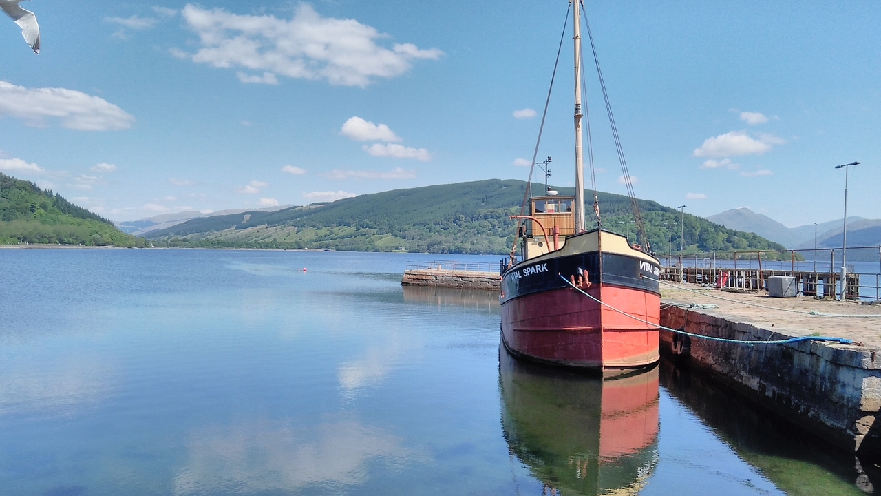 Bateau amarré à un lac serein avec des collines en arrière-plan.