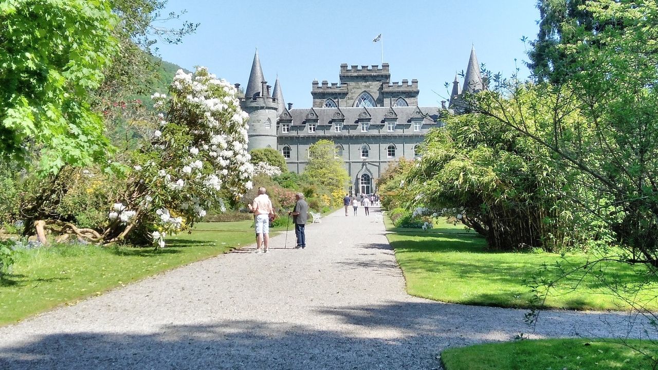 Château avec des jardins pittoresques et des gens qui se promènent.
