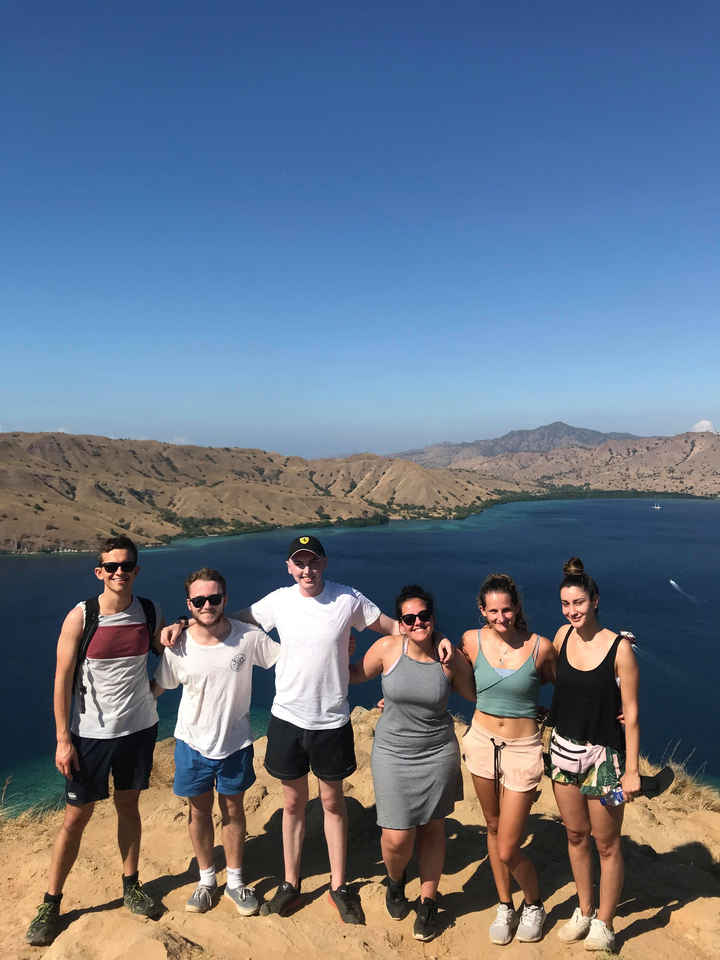 Group enjoying a scenic view from a hill overlooking the sea.