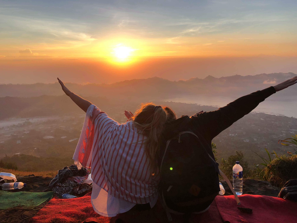 Silhouette of two people enjoying a sunset view from a mountain or hill.