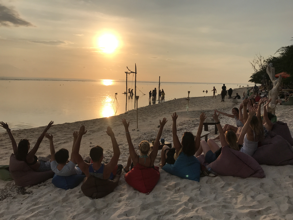 Beachgoers watching the sunset seated on loungers.