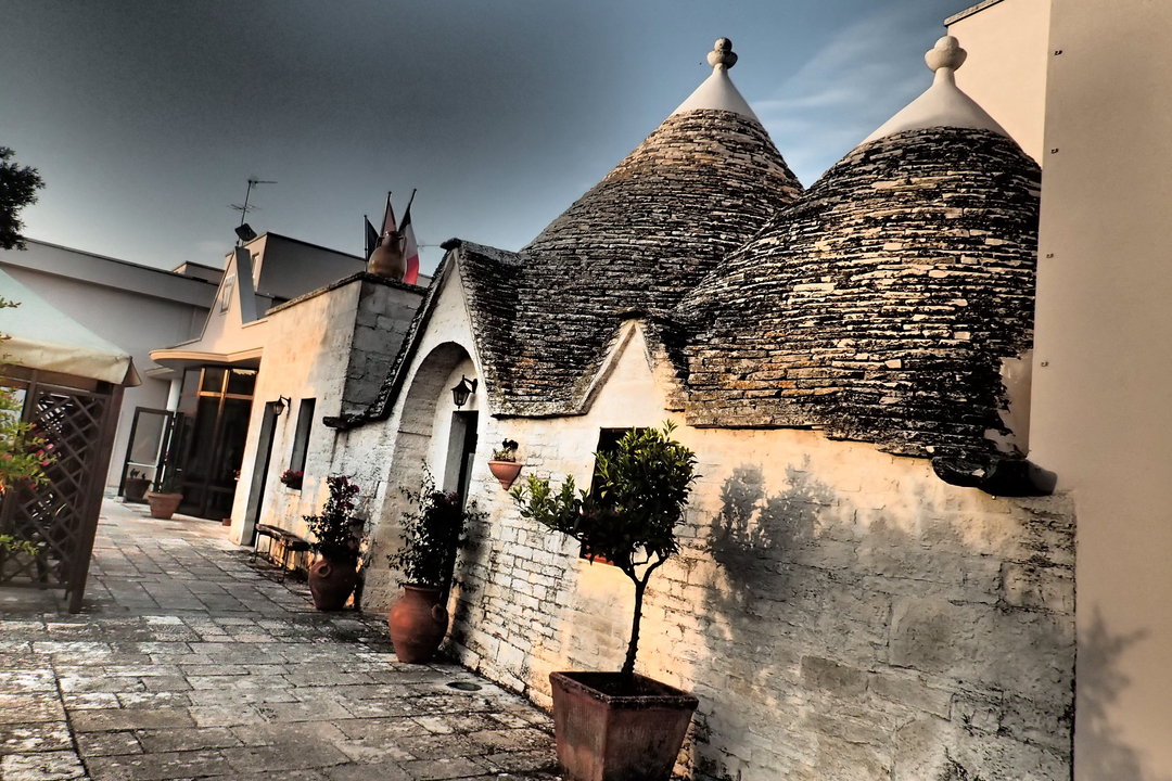 Des trulli traditionnels avec des toits en cône de pierre dans un cadre ensoleillé.