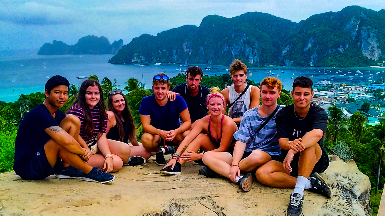 Group of people posing on a hill with an ocean view in the background.