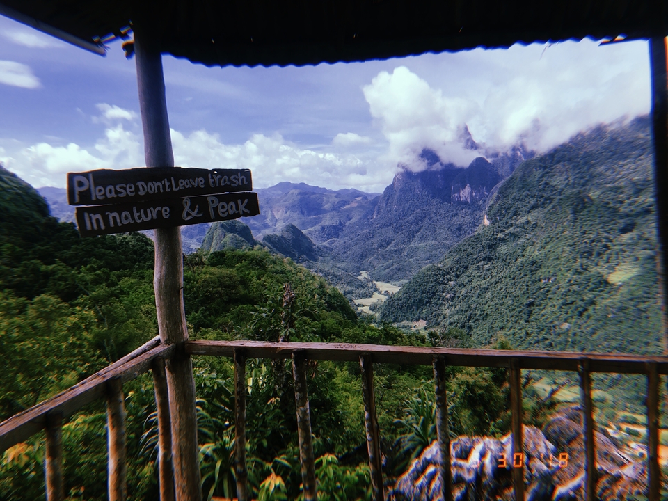 Scenic view over valleys and mountains with a wooden sign.