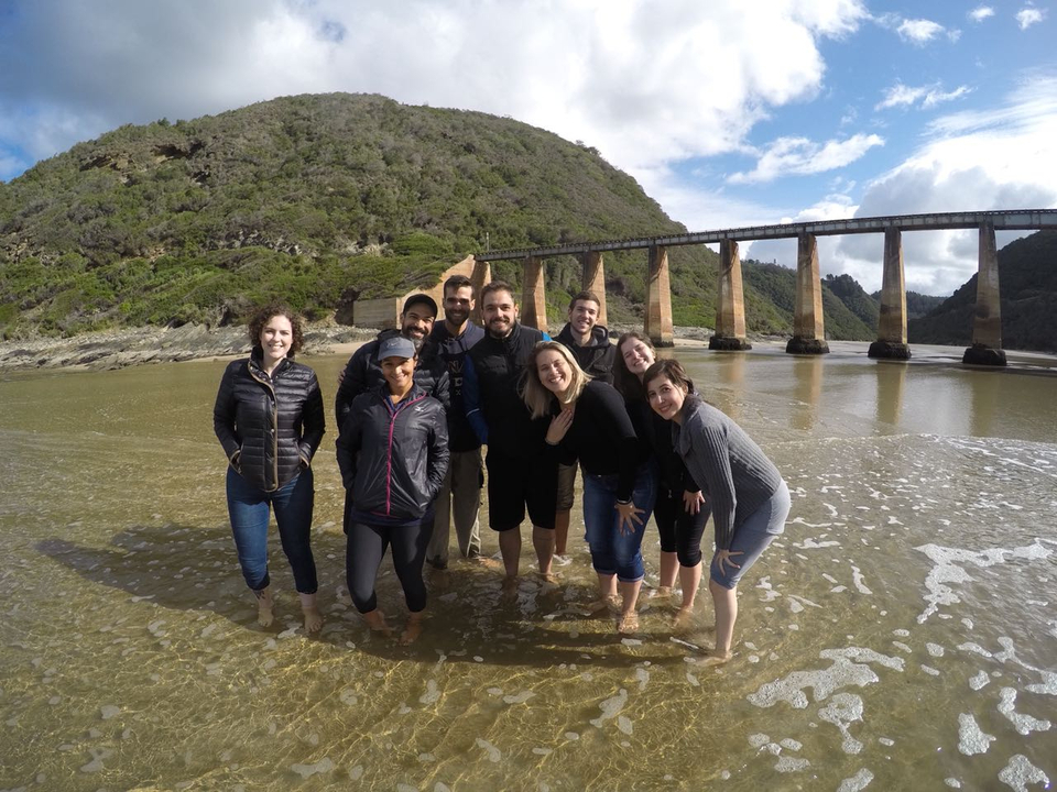 Groupe de personnes se tenant dans une eau peu profonde près d'un pont.