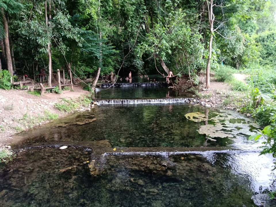 A tranquil stream with small waterfalls surrounded by greenery.
