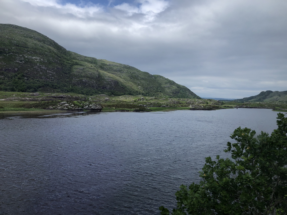 Vue panoramique d'un lac avec des collines verdoyantes.