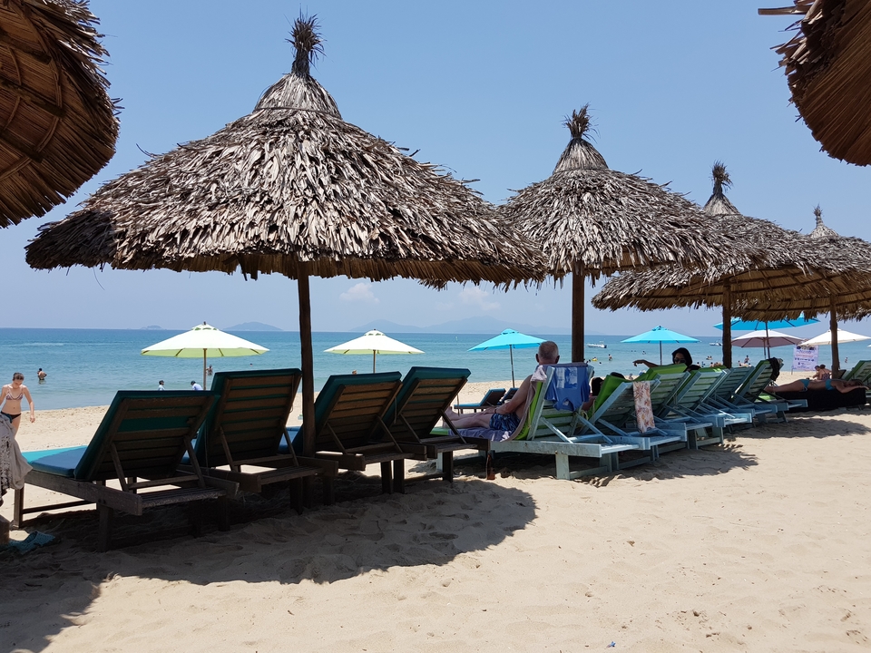 Plage avec chaises longues et parasols.