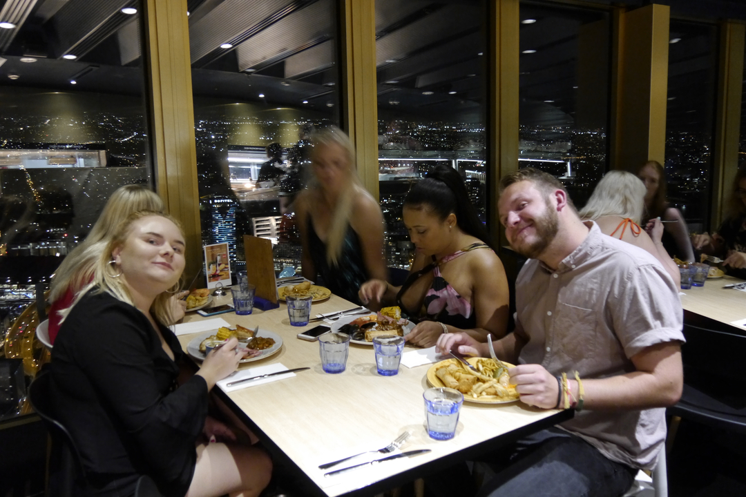 Group of friends dining in a cityscape setting with night view.
