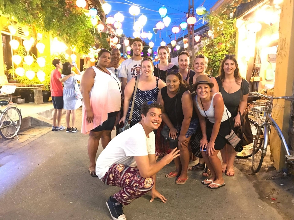 Groupe de personnes posant avec des lanternes colorées décorant la rue.