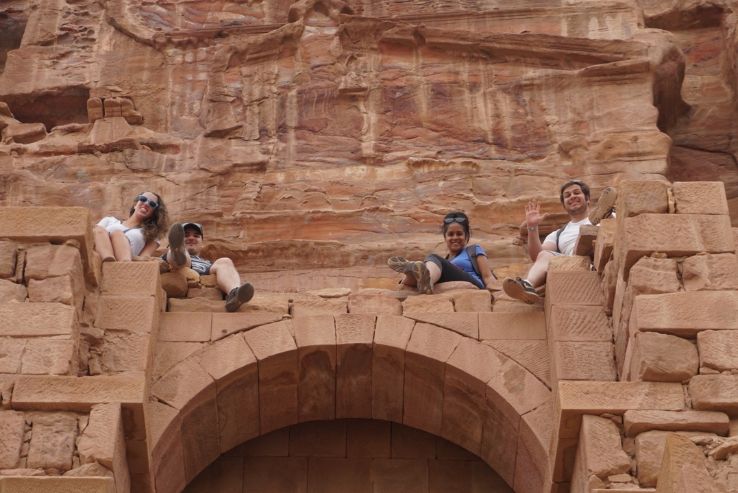 Quatre personnes assises sur d'anciennes ruines avec des roches rouges.