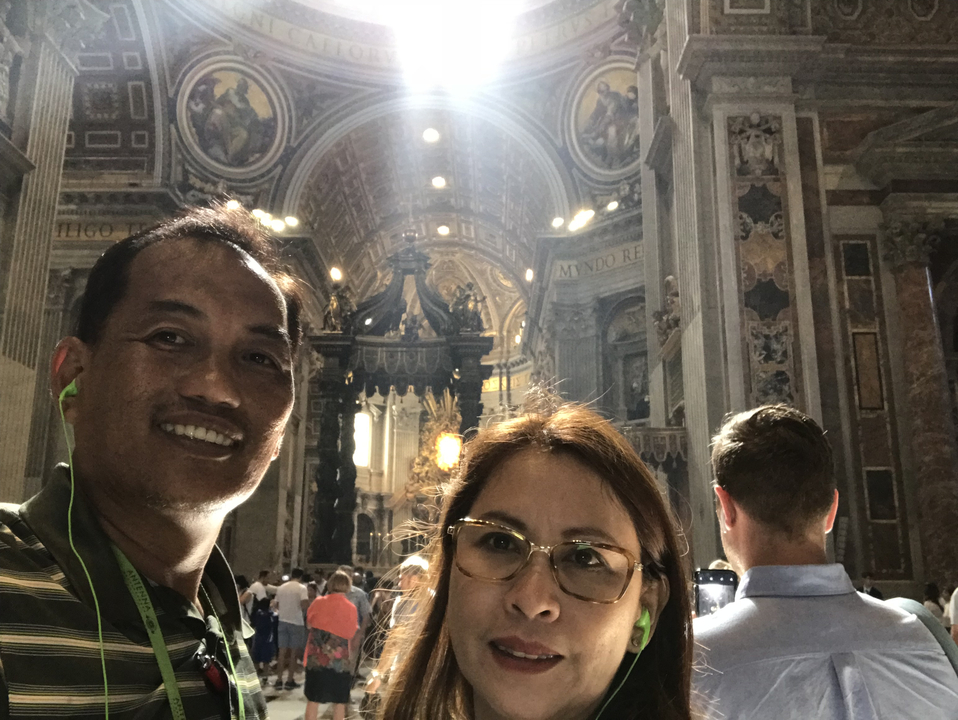 Two people posing inside a large basilica.
