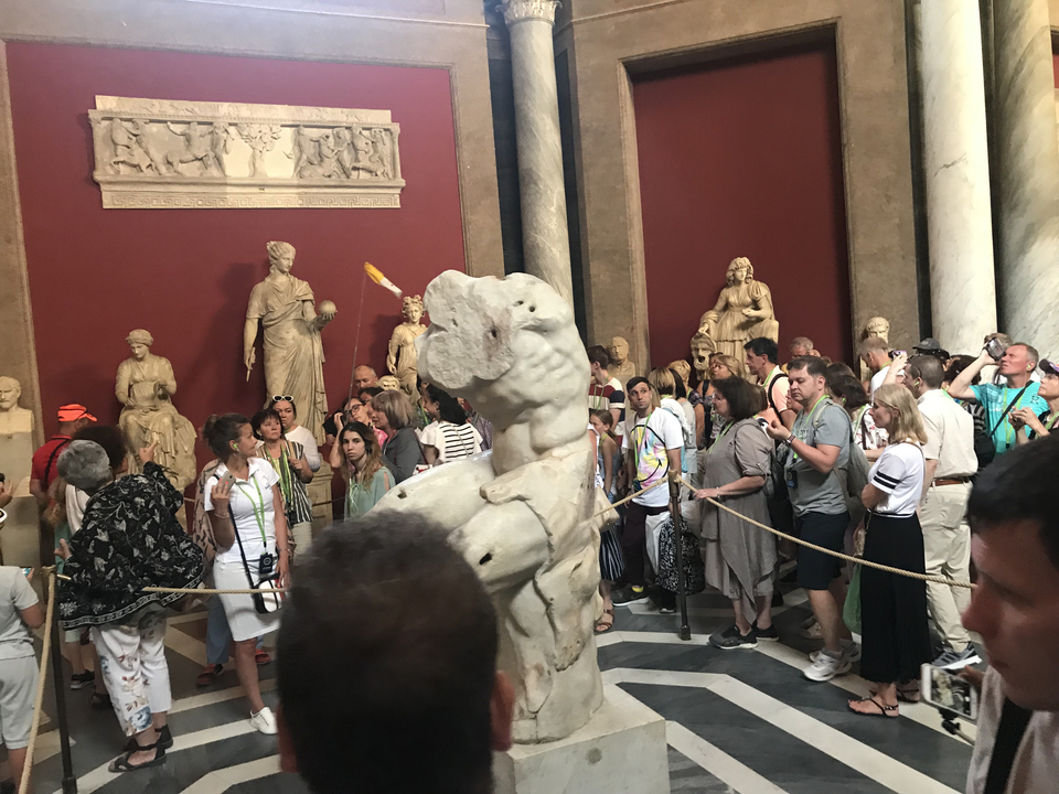 Crowded museum hall with large sculptures and statues.
