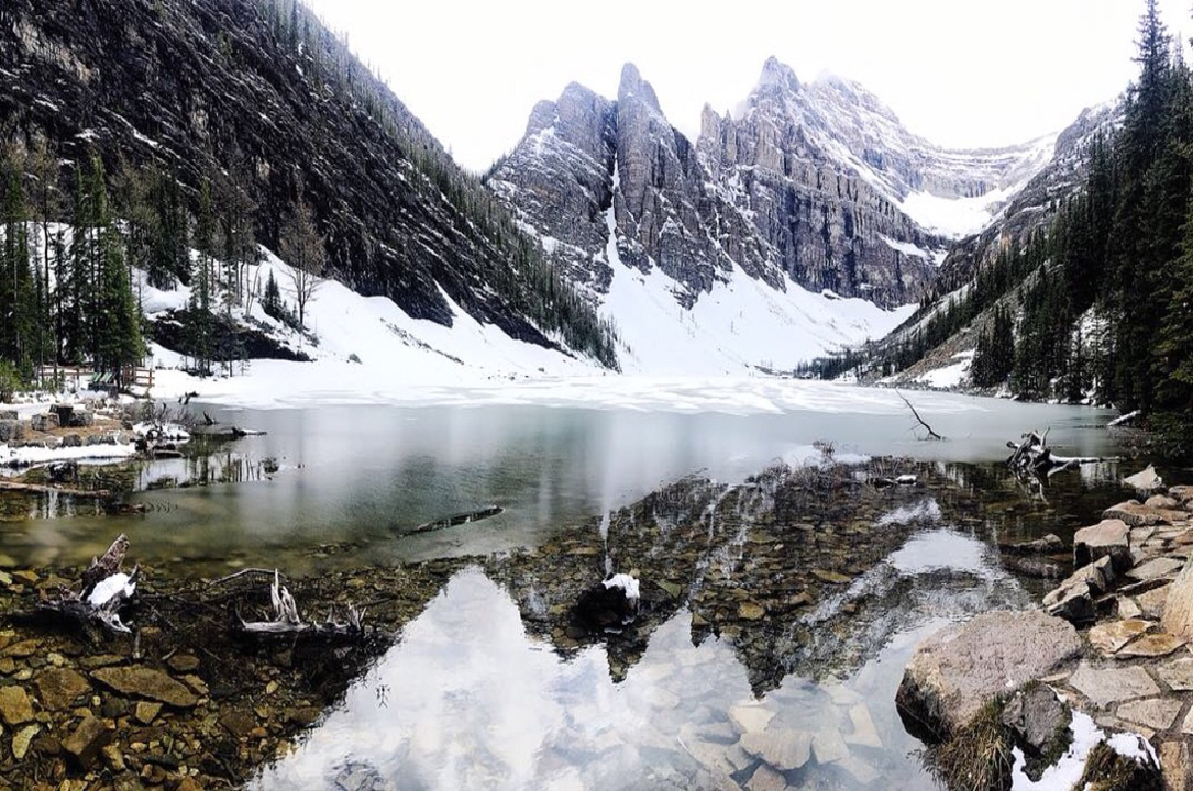 Frozen lake surrounded by snow-capped mountains.