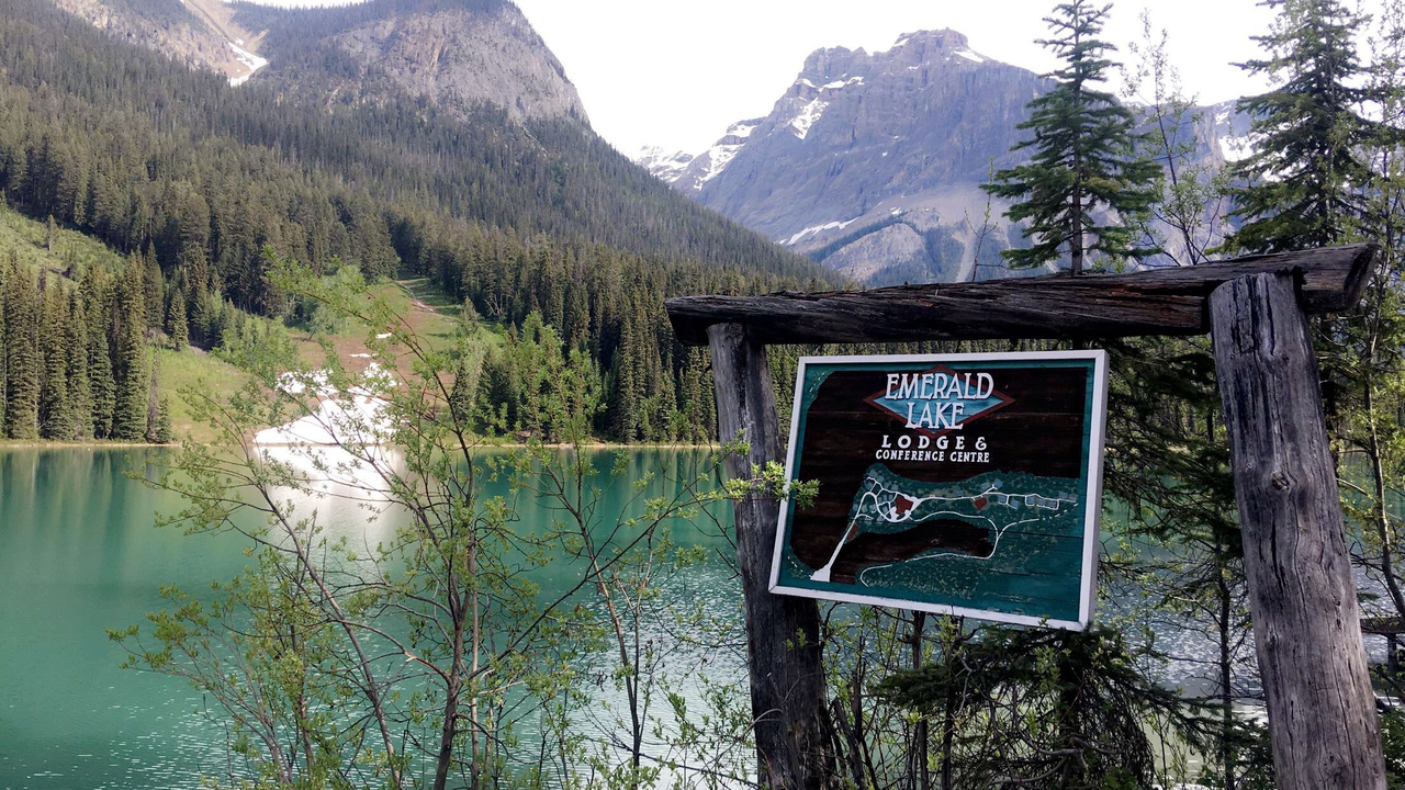 Schild für Emerald Lake mit Bergen im Hintergrund.