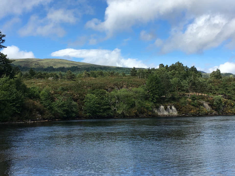 Vue d'un paysage avec une rivière et des collines verdoyantes.