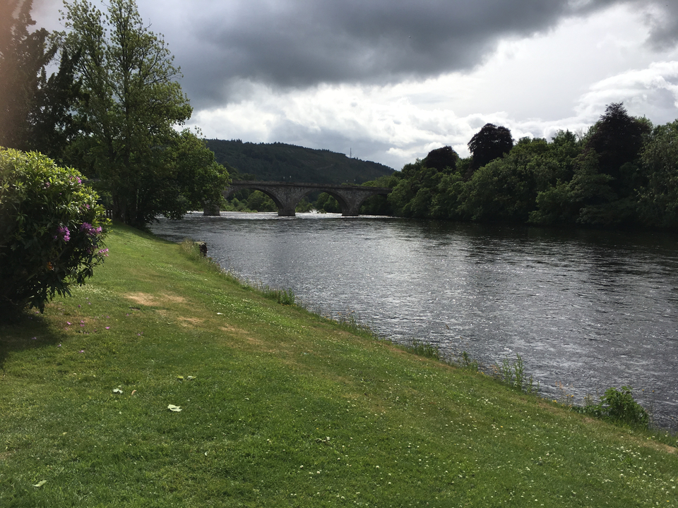 Scenic river with a stone bridge and lush greenery.
