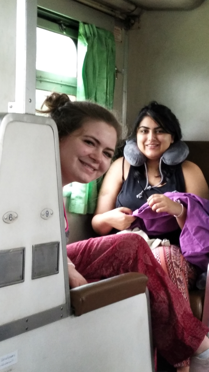 Two women smiling inside a train compartment.
