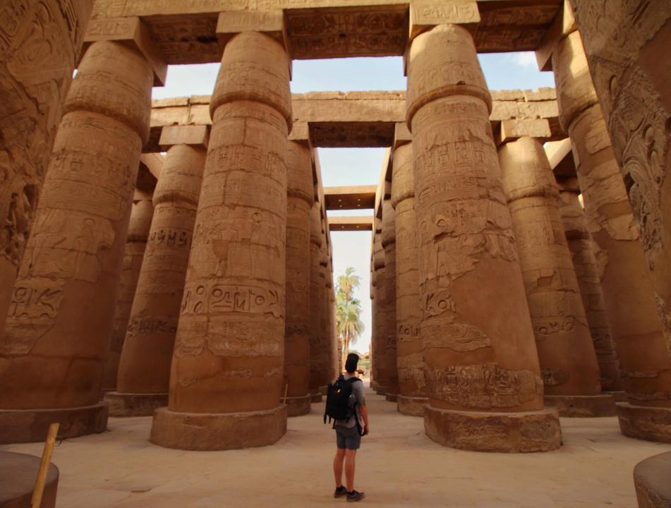 Tourist walking through ancient pillars with hieroglyphs