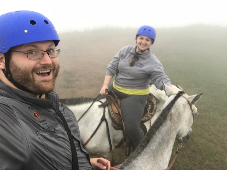 Couple à cheval dans le brouillard, portant des casques bleus.