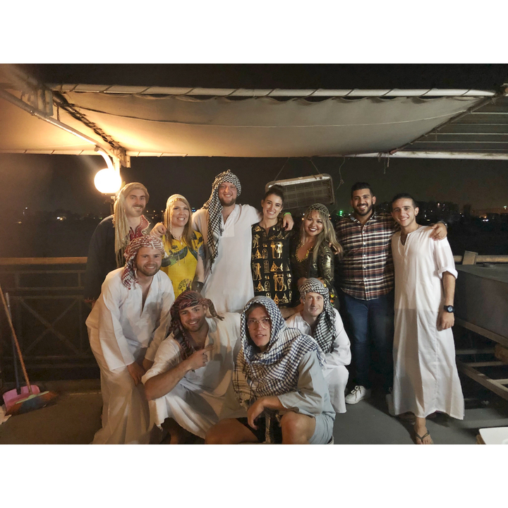 Photo de groupe de personnes portant des vêtements du Moyen-Orient sur un bateau, la nuit.