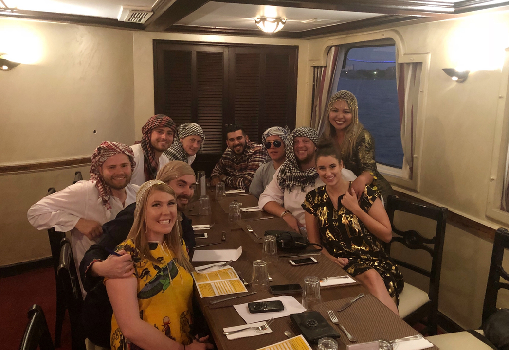 Groupe de personnes portant des vêtements traditionnels du Moyen-Orient lors d'un dîner à l'intérieur d'un bateau.