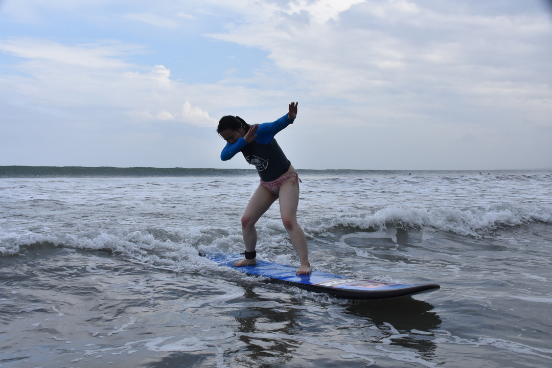 Person surfing a wave, balancing on a surfboard.